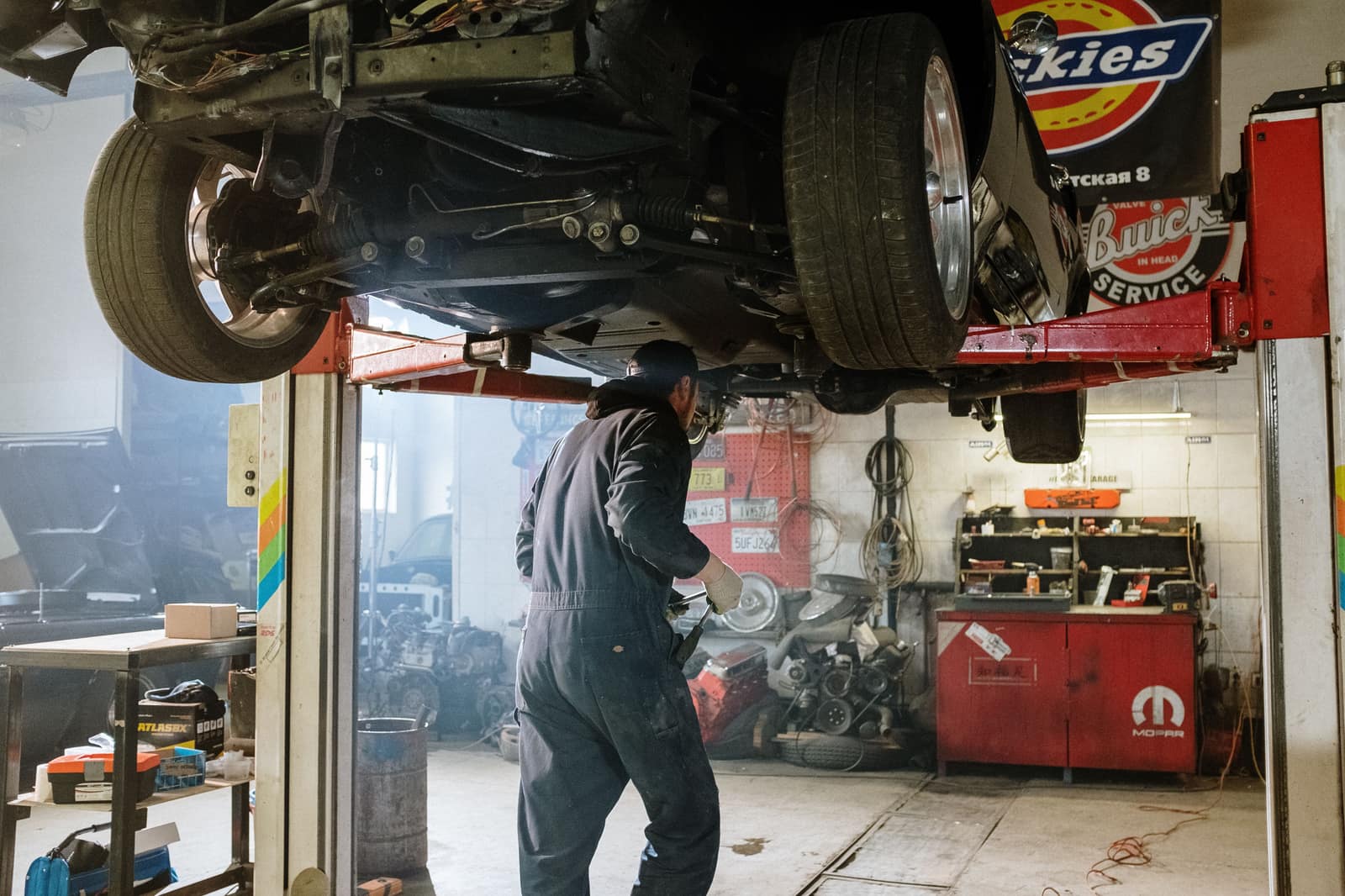 Mecánico trabajando debajo de un auto en el elevador